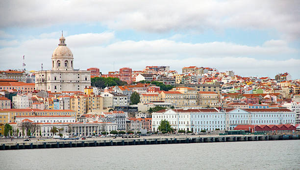 Stock Photo of Lisbon Cityscape with Church of Santa Engrácia Old Lisbon, Portugal cityscape as seen from the River Tagus. Amongst the traditional red tiled roofs the Church of Santa Engrácia can be seen to the left.  The seventeenth century church was converted into National Pantheon in the early twentieth century and now many famous Portuguese are buried there.  To the bottom right on the image is the Santa Apolonia train station. national pantheon lisbon stock pictures, royalty-free photos & images