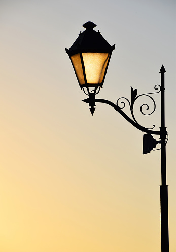 Street antique style lamp post with effect of shine from low light of sunset