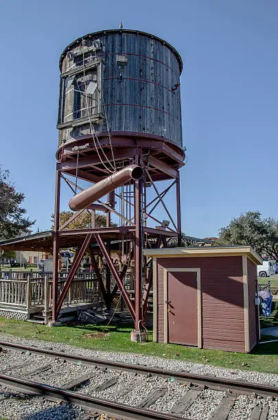 A water tower stands along the railroad tracks