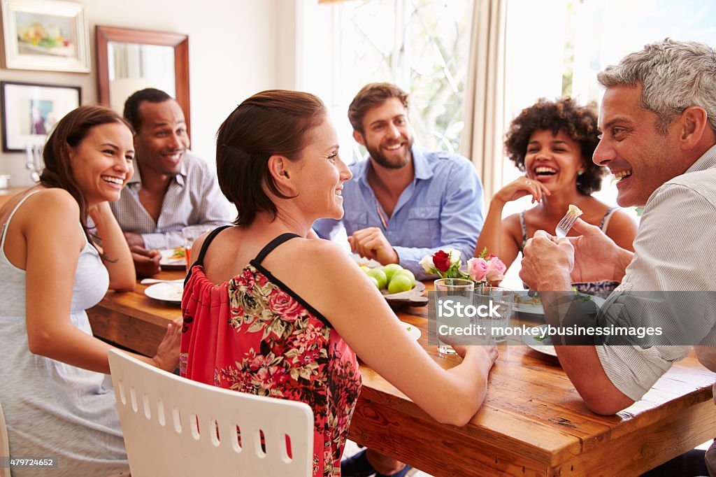 Friends sitting at a table talking during a dinner party Domestic Life Stock Photo