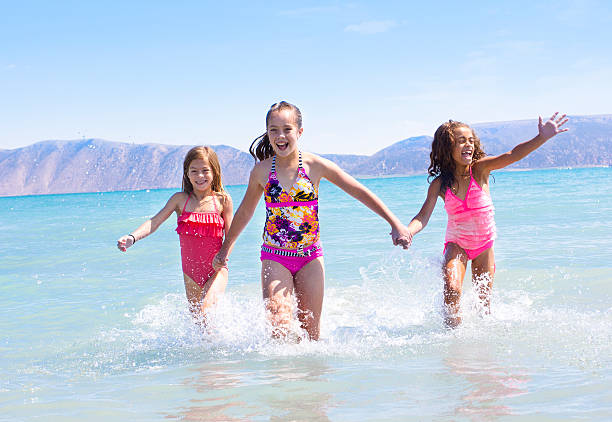 Three kids splashing in the water and playing in the ocean while on vacation
