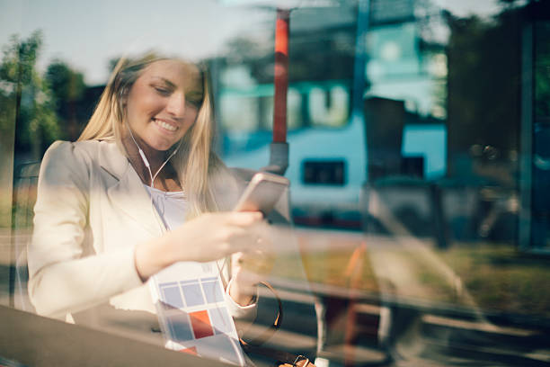 若い女性は彼女のスマートフォン入力にの公共交通機関です。 - bus inside of people train ストックフォトと画像