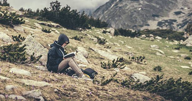 istock Woman reading a book sitting on a grass 479729714