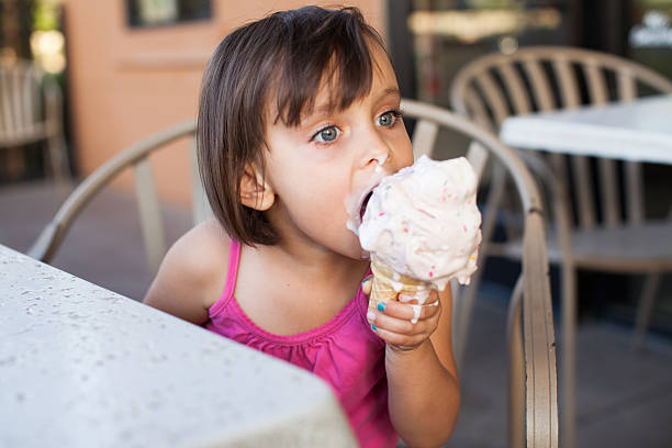 маленькая девочка ест мороженым - one baby girl only фотографии стоковые фото и изображения