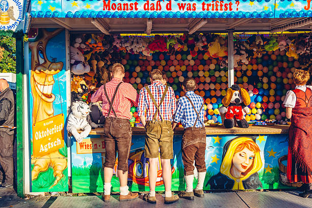 Munich, Germany - October 2, 2013: People, dressed in typical leather trousers  are standing at a shooting gallery at the Oktoberfest. The Oktoberfest in Munich is the biggest beer festival of the world.