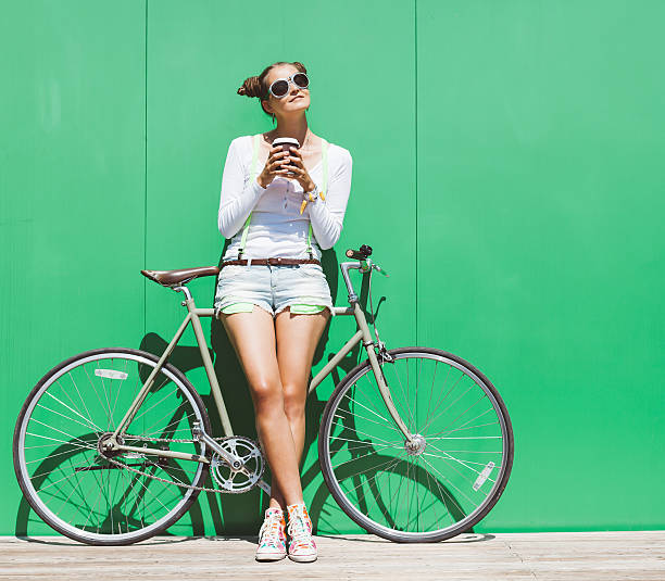 modische mädchen in shorts ist mit fahrrad fix ausrüstung - women street dress city stock-fotos und bilder