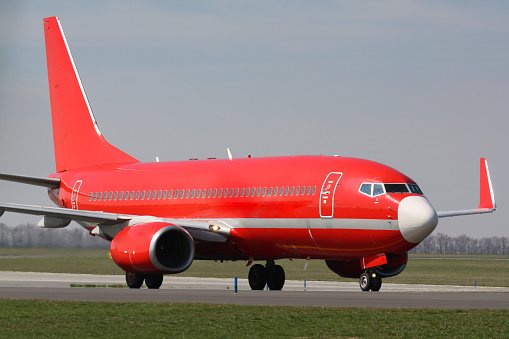 Red plane taxiing after landing to terminal
