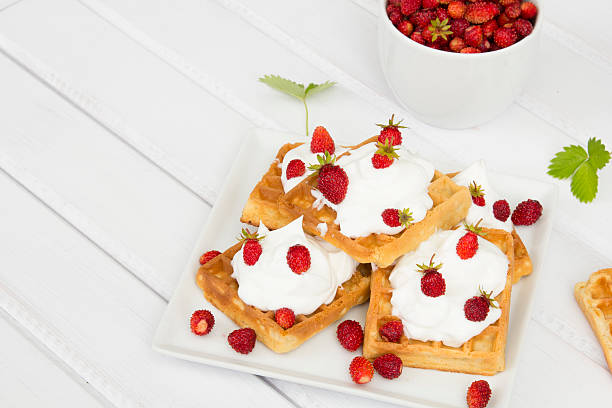 istock waffles with wild strawberries and whipped cream on white table 479750452