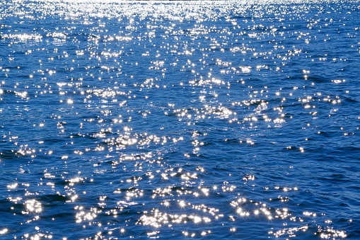 View of the water surface of the ocean with sun light glistening from the waves