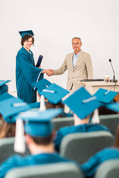 istock Graduation student shaking hands with professor and looking at camera, 479765200
