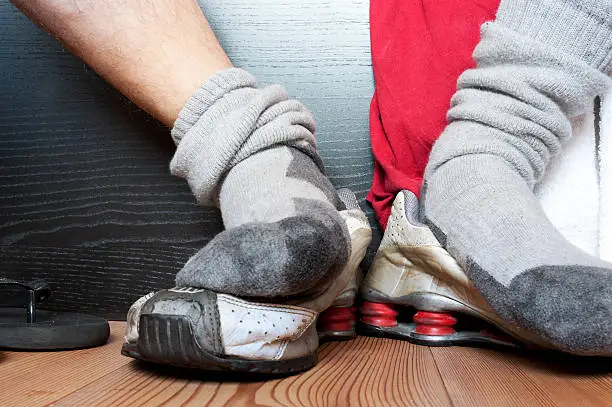 Close-up view of sweaty socks after workout over a pair of worn out dirty shoes.