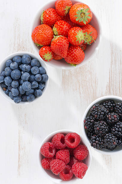istock Fresh berries in bowl on white wooden background, top view 479774502