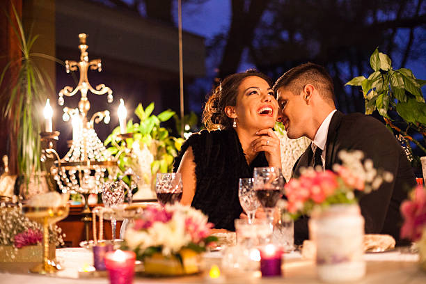 Young couple having dinner at a restaurant. Young couple having romantic dinner at the restaurant. Woman is laughing while man whispering something at her ear. candle light dinner stock pictures, royalty-free photos & images