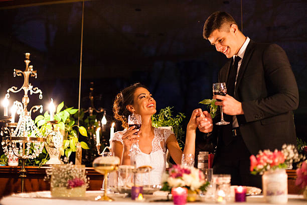 Bride and groom toasting with red wine on wedding ceremony Bride and groom toasting with red wine on wedding ceremony. Smiling groom is holding bride's hand, looking at her eyes. wedding ceremony formalwear people clothing stock pictures, royalty-free photos & images