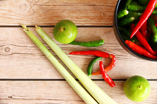 Thai Tom Yam soup herbs and spices, consisting of lemongrass, Kaffir Lime leaves, Galangal, Lemon and Red Chilli on an old wooden table.