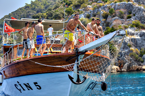Antalya, Turkey - August 28, 2014: Water tourism, excursion walk on a yacht in the Mediterranean Sea, Turkish men and a woman relaxing on the deck of a tourist boat on a sunny summer day.