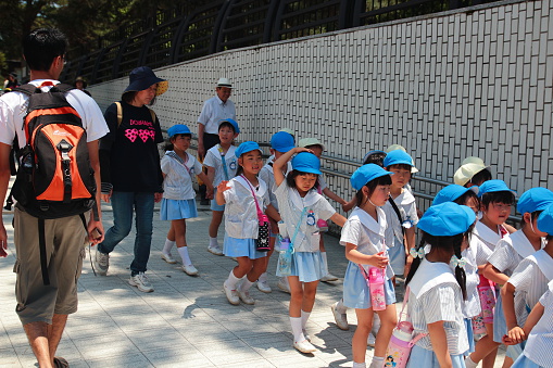 Nara, Japan - May 30, 2015: School children group walking in a park together with their educators.