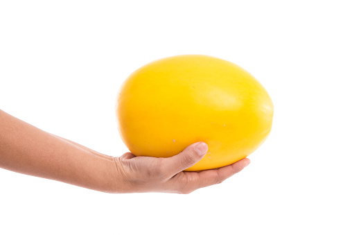 Female's hand holding honeydew melon on a white background isolated