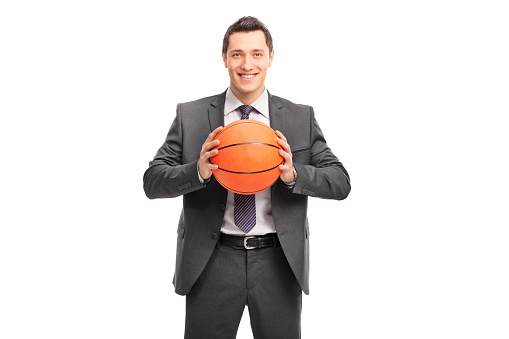 Young cheerful businessman holding a basketball and looking at the camera isolated on white background