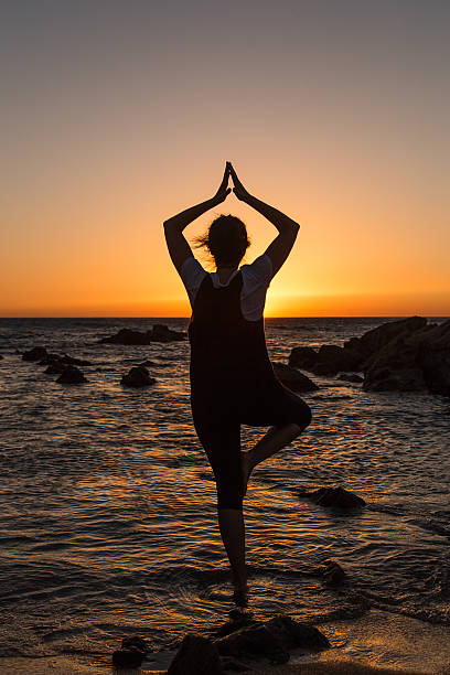 istock Silhouette young woman practicing yoga on the beach at sunset. 479799806