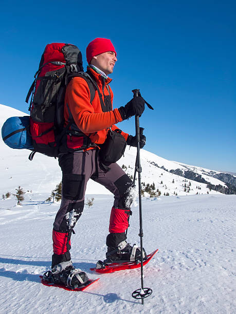 The man in snowshoes in the mountains. The man in snowshoes and with trekking poles is in the mountains. snowshoeing snow shoe red stock pictures, royalty-free photos & images