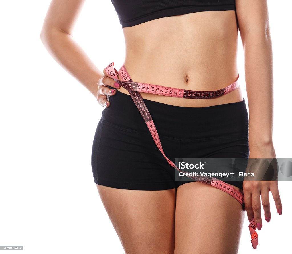 Girl measuring waistline. Young slim woman measuring waist circumference, after a diet. Isolated on white background. The concept of excess weight loss and healthy eating. 2015 Stock Photo