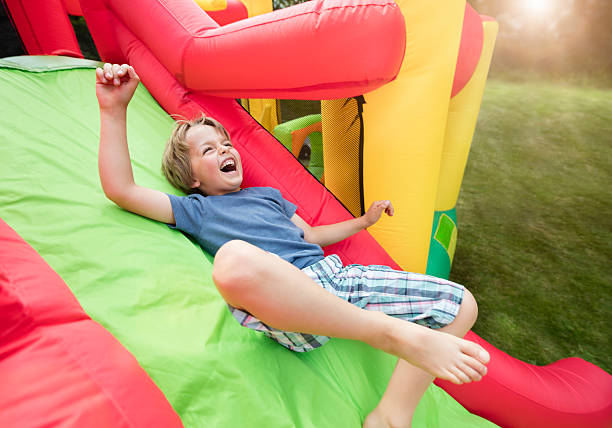 Child on inflatable bouncy castle slide Boy jumping down the slide on an inflatable bouncy castle sliding photos stock pictures, royalty-free photos & images
