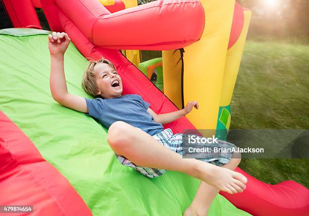 Child On Inflatable Bouncy Castle Slide Stock Photo - Download Image Now - Bouncy Castle, Child, Inflatable