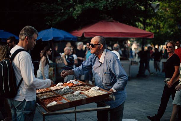 Athens, Greece - July 3, 2015: Senior man selling dried nuts during a protest in Syntagma Square, Athens Greece. He is giving change to a customer. Still in Euros.