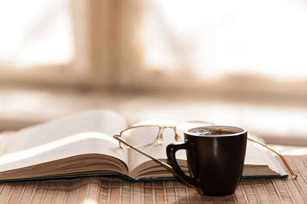 istock cup of coffee, standing next to an open book 479818690