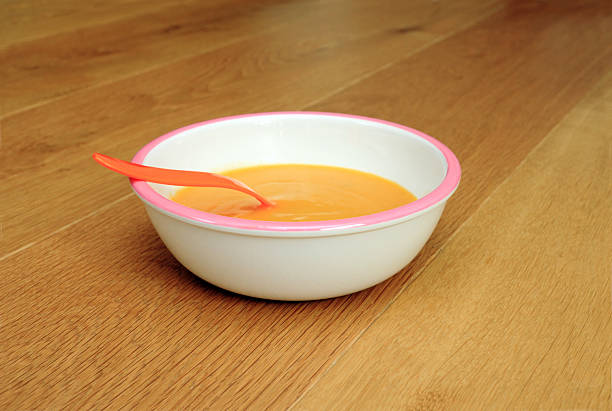 Bowl of soup in a children's bowl, on wooden ground