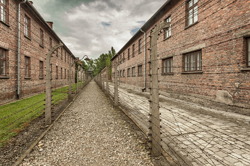 Oswiecim, Poland - June 28, 2015: Barbed wire fence and brick buildings (so called blocks) in Auschwitz I. concentration camp. No visitors around.