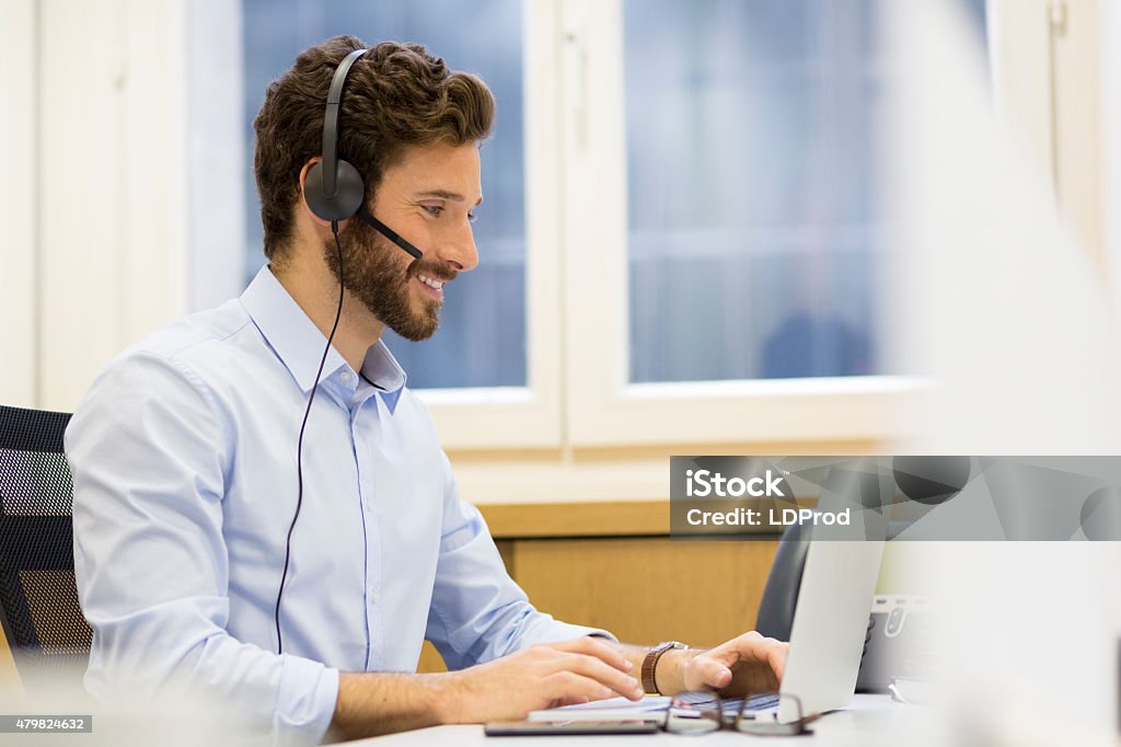 Happy Businessman in the office on the phone, headset, Skype Close up of a hipster man in conference call on laptop at his desk Men Stock Photo