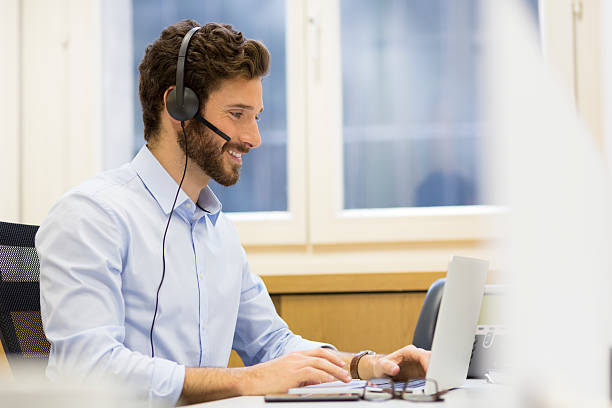 feliz empresário no escritório no telefone, fones de ouvido, skype - skype - fotografias e filmes do acervo