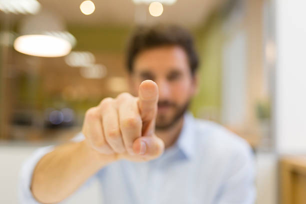 Man hand pushing a digital screen on office background A man pointing his finger on digital touch computer, facing camera clicking screen stock pictures, royalty-free photos & images
