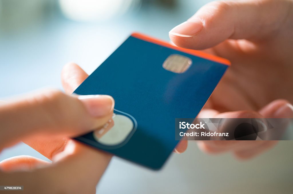 Buying with Credit Card Closeup shot of a woman passing a payment credit card to the seller. Girl holding a credit card. Shallow depth of field with focus on the credit card. Credit Card Stock Photo