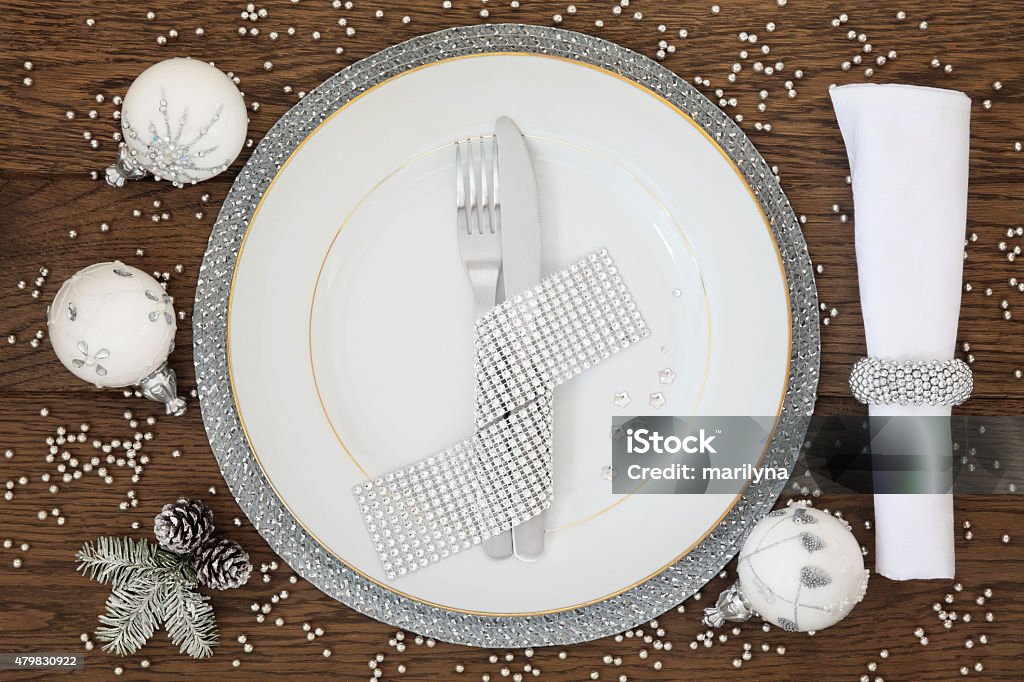 Christmas Bling Christmas holiday dinner place setting with plate, napkin, cutlery, sparkling bauble decorations over oak table background. 2015 Stock Photo