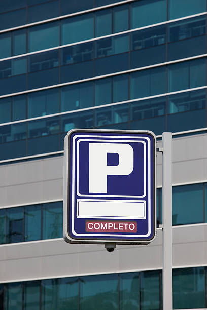 istock Parking signpost with completo text and modern building backgrou 479834804