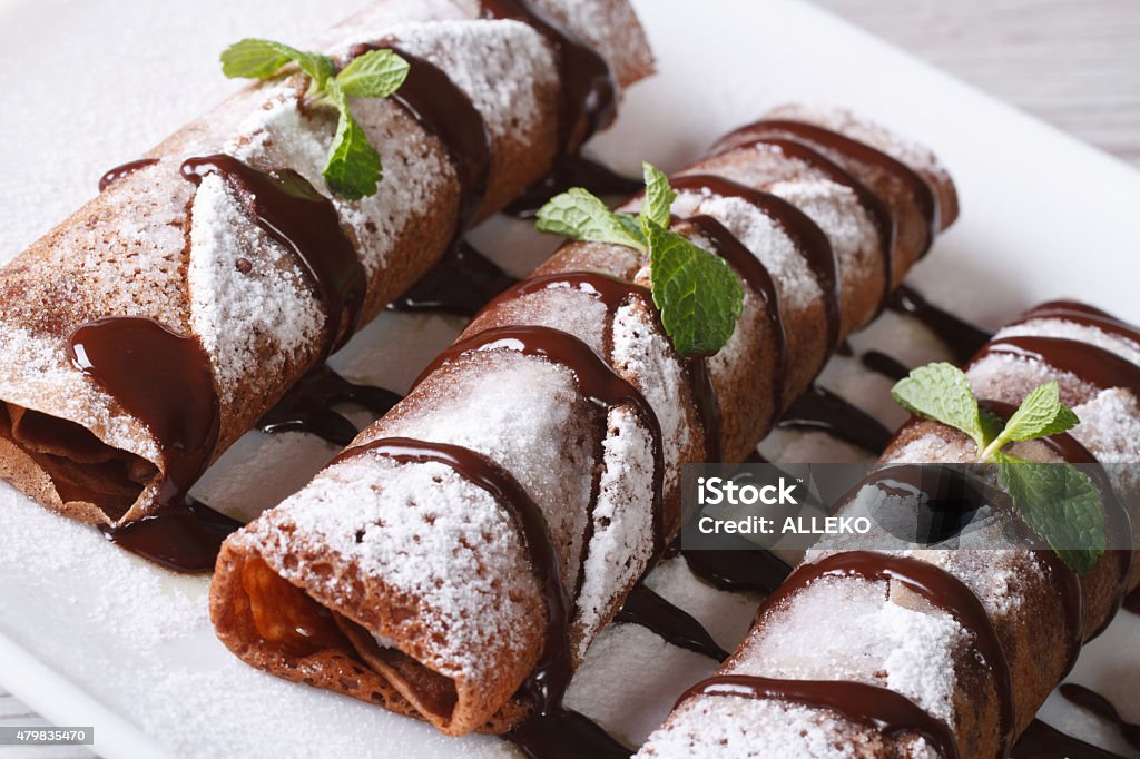 chocolate crepes with sauce and mint close up horizontal chocolate crepes with sauce and mint close up on a plate. horizontal Cacao Fruit Stock Photo