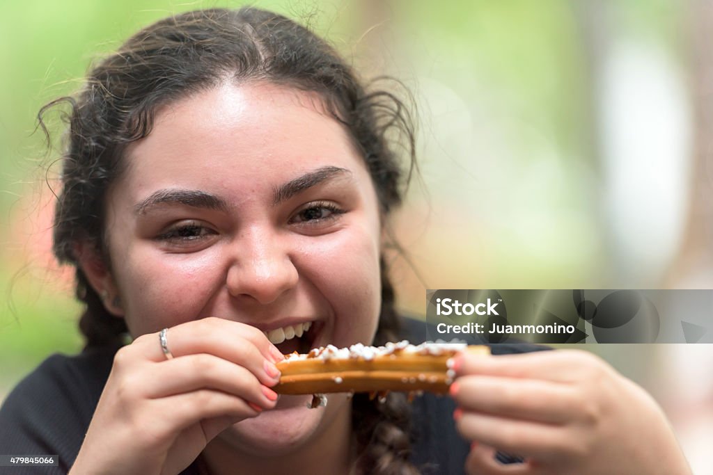 Teenage Hispanic Girl Having a Churro Lifestyle image of a Smiling fifteen Years Old Hispanic Girl Having a Churro 14-15 Years Stock Photo