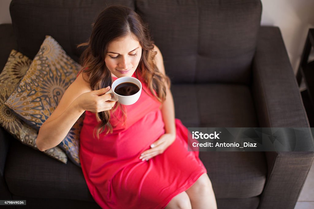 Drinking some coffee at home High angle view of a young pregnant woman drinking a cup of coffee at home Coffee - Drink Stock Photo