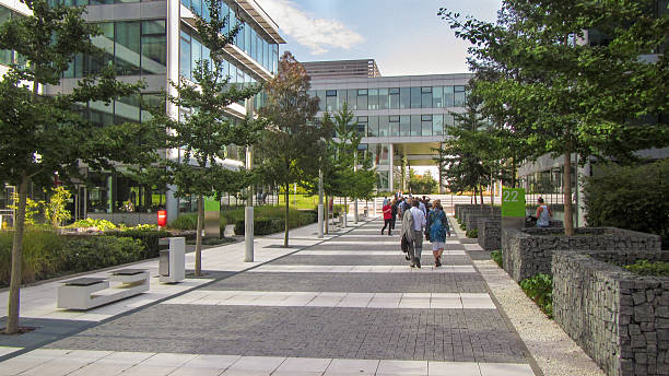 Pedestrian area in a modern business park Prague, Czech Republic - September 19, 2014: Pedestrian area in a modern business park. People are walking. Trees ans office buildings along the street, image created 21st century blue architecture wide angle lens stock pictures, royalty-free photos & images