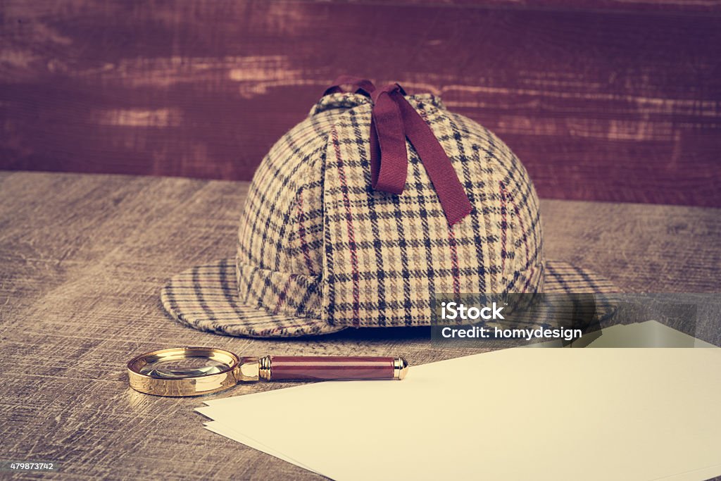 Sherlock Hat and magnifying glass Deerstalker or Sherlock Hat and magnifying glass on Old Wooden table. Sherlock Holmes Stock Photo