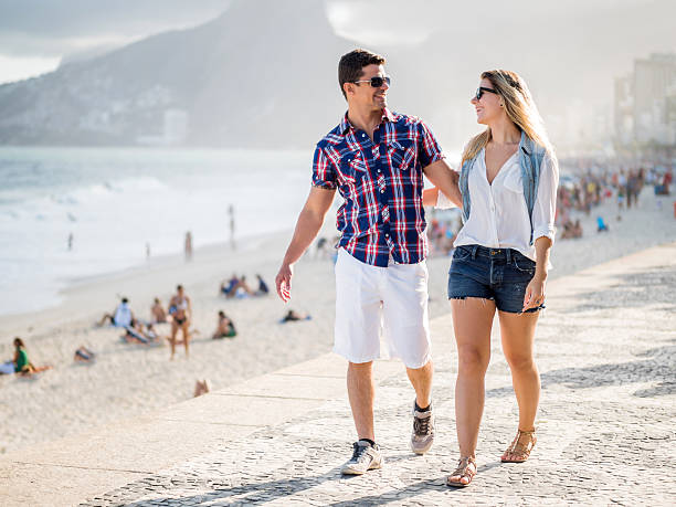 istock Embraced couple walking on coastline during summer day and talking. 479875930