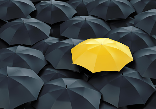 Unique yellow umbrella among many dark ones. Standing out from crowd, individuality and difference concept.