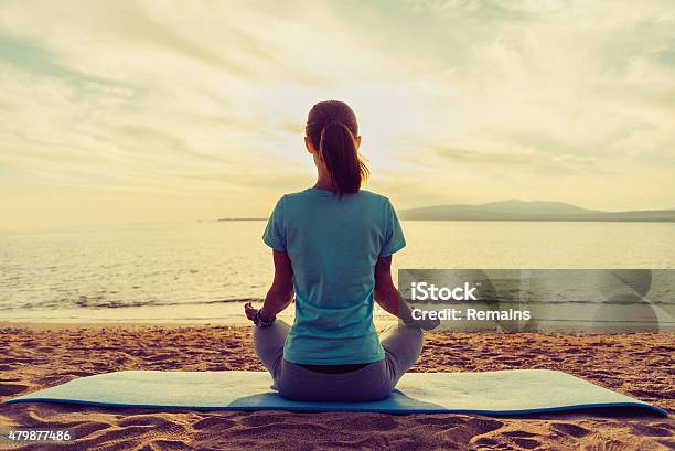 Girl Meditating In Pose Of Lotus On Beach Stock Photo - Download Image Now - 2015, Activity, Adult