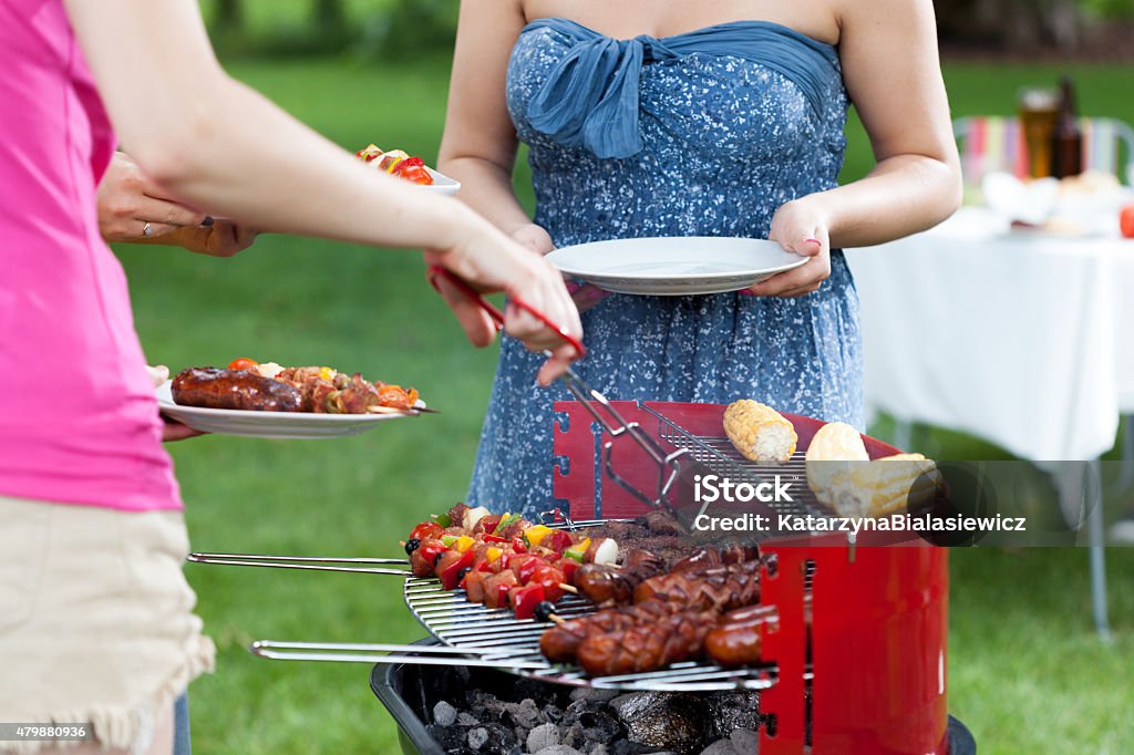 Host serving meals on barbecue party Host serving grilled meals on barbecue party 2015 Stock Photo