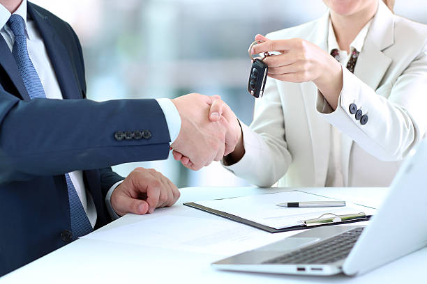 Car saleswoman handing over the keys for a new car stock photo
