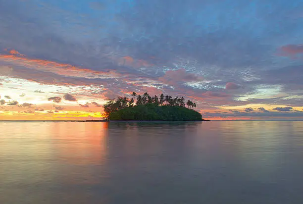 The small remote Taakoka Island in the Cook Islands during a colourful sunrise.