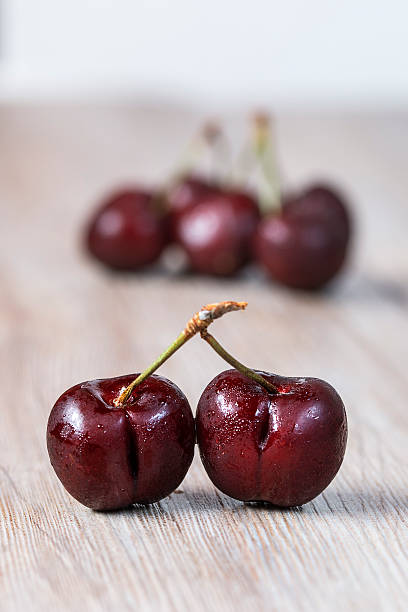 Two cherries over wooden background